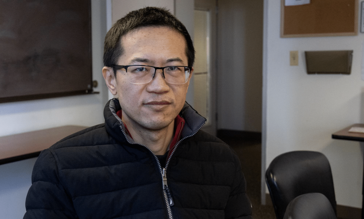 Changwu Wang, a second-year student at the Pacific College of Health and Science, sits at a table in a classroom.